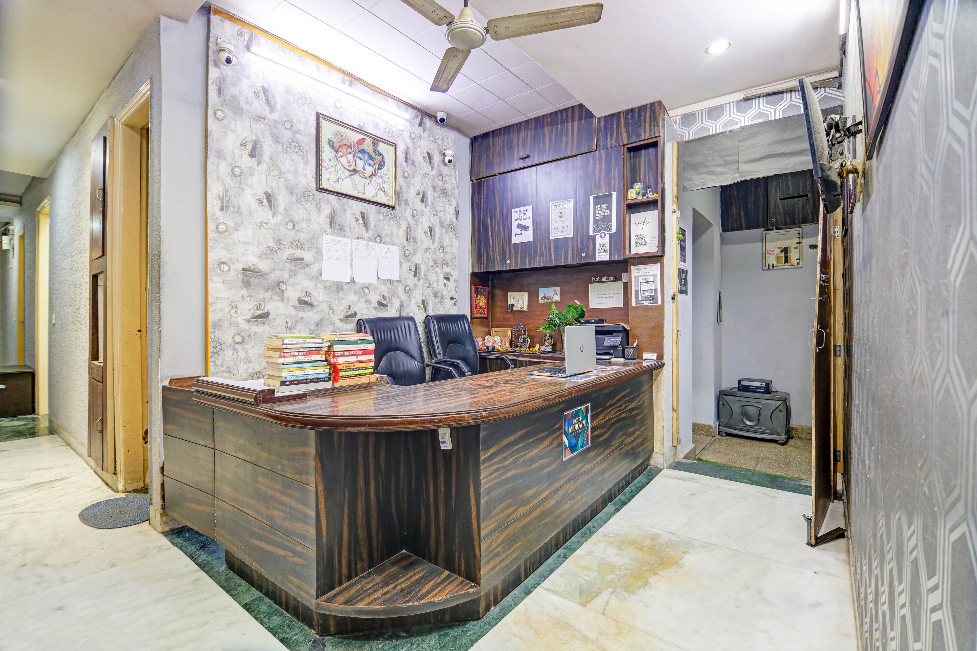 Una recepción con detalles de madera, un ventilador de techo y una pared con diplomas enmarcados.