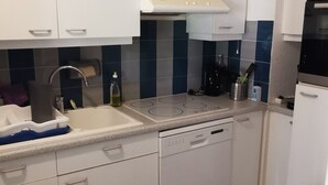 A modern kitchen with white cabinets, a dishwasher, a stove, and a sink.