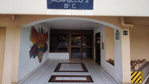 A building entrance with a sign reading 'ACAPULCO 2 B'T C,' a tiled floor, and a mural on the wall.