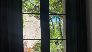 Una finestra con vista su un giardino, che comprende un tavolo e sedie rossi e un muro in pietra.