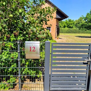 A metal gate with a mailbox labeled '12' in front of a brick building.