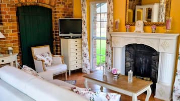 Ein Wohnzimmer mit Backsteinwand, Kamin, Fernseher und Sofa.