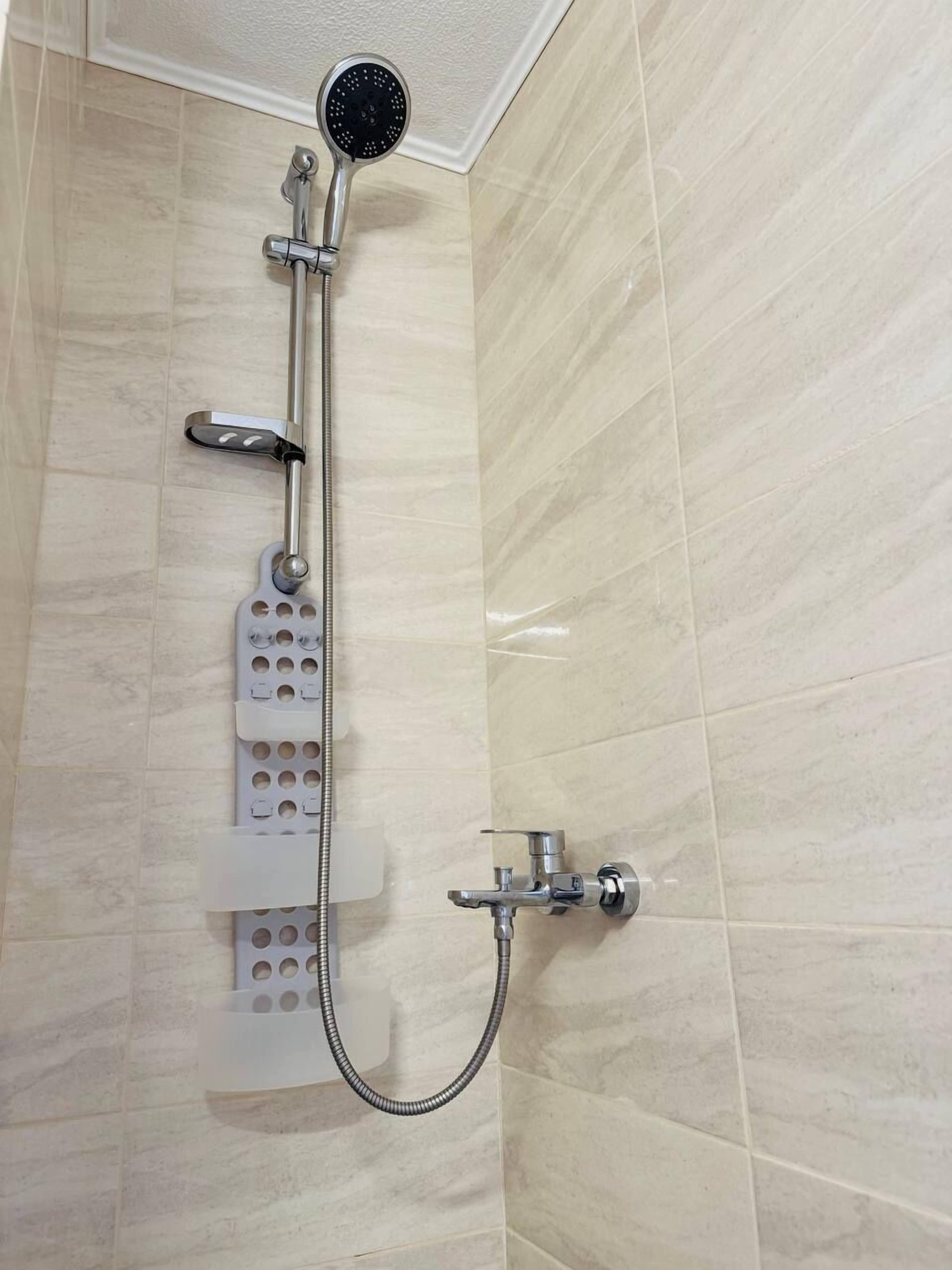 A shower with a handheld showerhead, a handheld shower attachment, and a wall-mounted faucet.