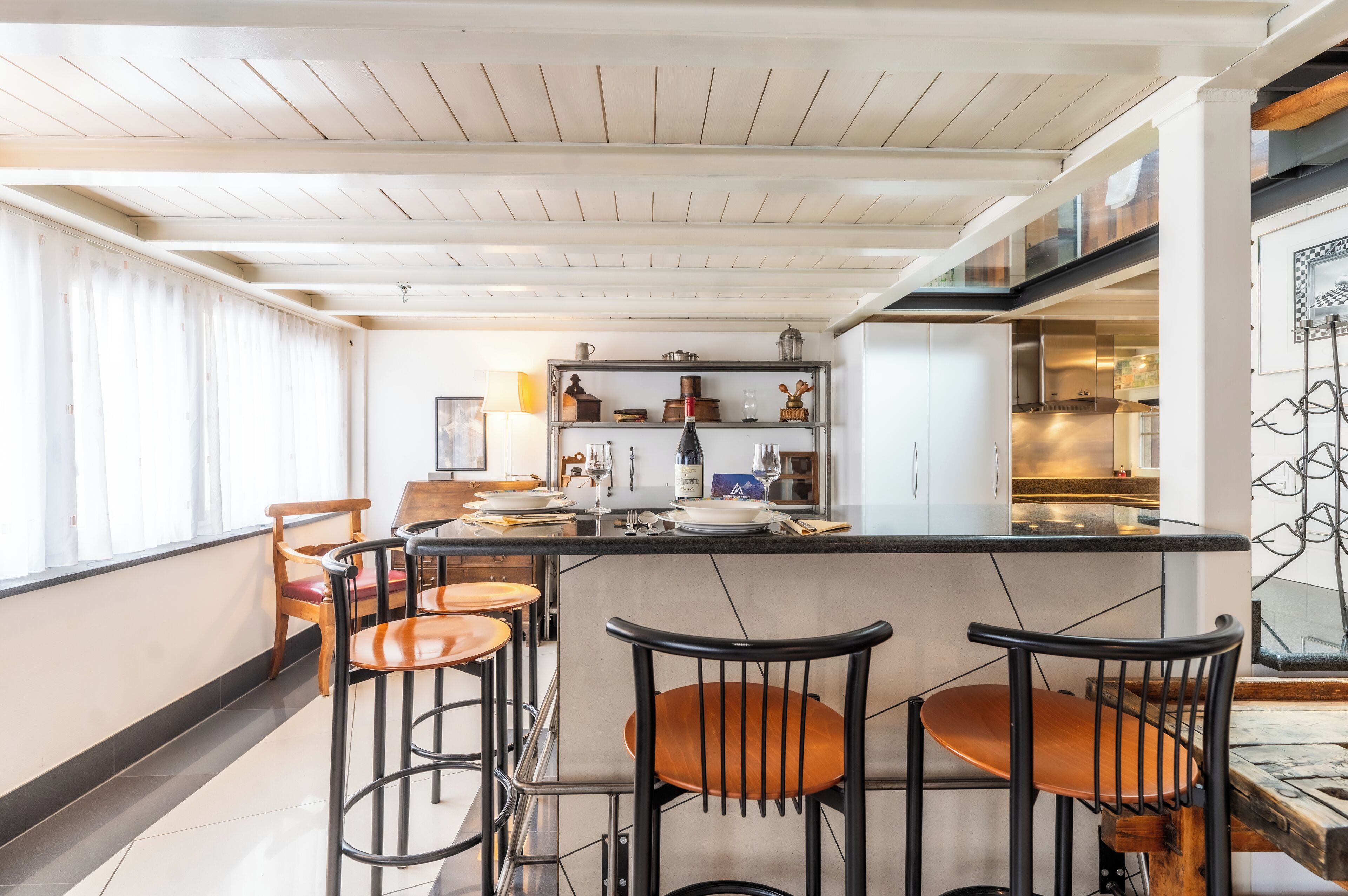 A modern kitchen with a bar area, wooden chairs, and a dining table.