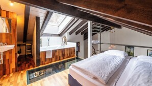 Une chambre à coucher moderne avec une lucarne, une salle de bain aux murs en verre et un plancher en bois.