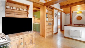 A wooden interior with a TV, shelves, and a kitchen area.