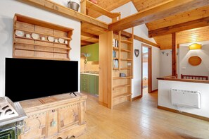 Ein Holzinnenraum mit Fernseher, Regalen und einer Küchenzeile.