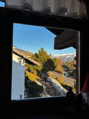 Blick durch ein Fenster auf eine Berglandschaft, eine Straße und ein Gebäude.