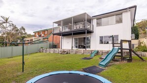 A two-story house with a balcony, a trampoline, and a slide in the backyard. - The Wreck Room, 6 Flannel Flower Fairway - fantastic house filled with activities for all (Shoal Bay)