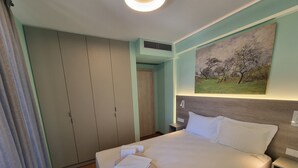 A hotel room with a bed, a nightstand, a painting, a wardrobe, and a door.