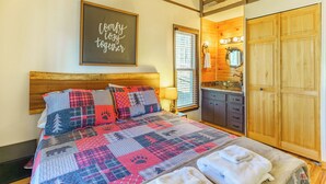 A cozy bedroom with a wooden headboard, a quilted bedspread, a wall-mounted mirror, and a wooden wardrobe. - 5 Mins to Ski Slopes & Restaurants Charming Beech Mountain Chalet 2BR + Loft (Beech Mountain)