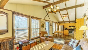 A spacious living room with a sofa, a wooden coffee table, and a fireplace. There is a kitchen area with wooden cabinets and a stove. - 5 Mins to Ski Slopes & Restaurants Charming Beech Mountain Chalet 2BR + Loft (Beech Mountain)