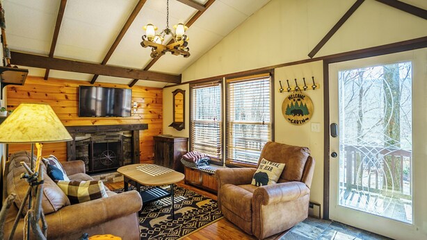 A cozy living room with a fireplace, wooden walls, and a large window. - 5 Mins to Ski Slopes & Restaurants Charming Beech Mountain Chalet 2BR + Loft (Beech Mountain)