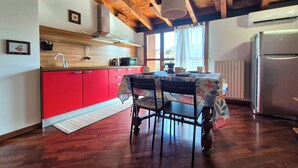 Una cocina con armarios rojos, techo de madera y una mesa de comedor con sillas.