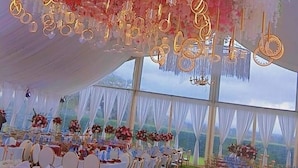 An indoor event space with white draped ceilings, tables set for a formal event, and hanging floral decorations. - Theta Country Resort (Juja)