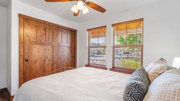 A bedroom with a large bed, wooden wardrobe, and a ceiling fan.