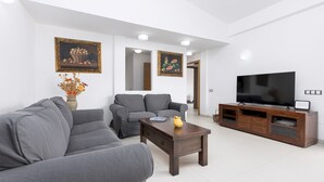 Una sala de estar moderna con sofás grises, una mesa de centro de madera y un televisor sobre un mueble de madera.