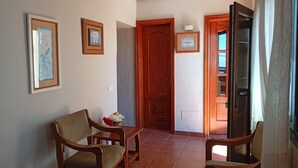 A living room with two wooden chairs, a small table, and a door leading to another room.