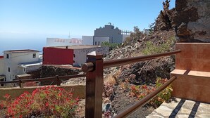 A view of a coastal area with buildings, a rocky cliff, and a railing.