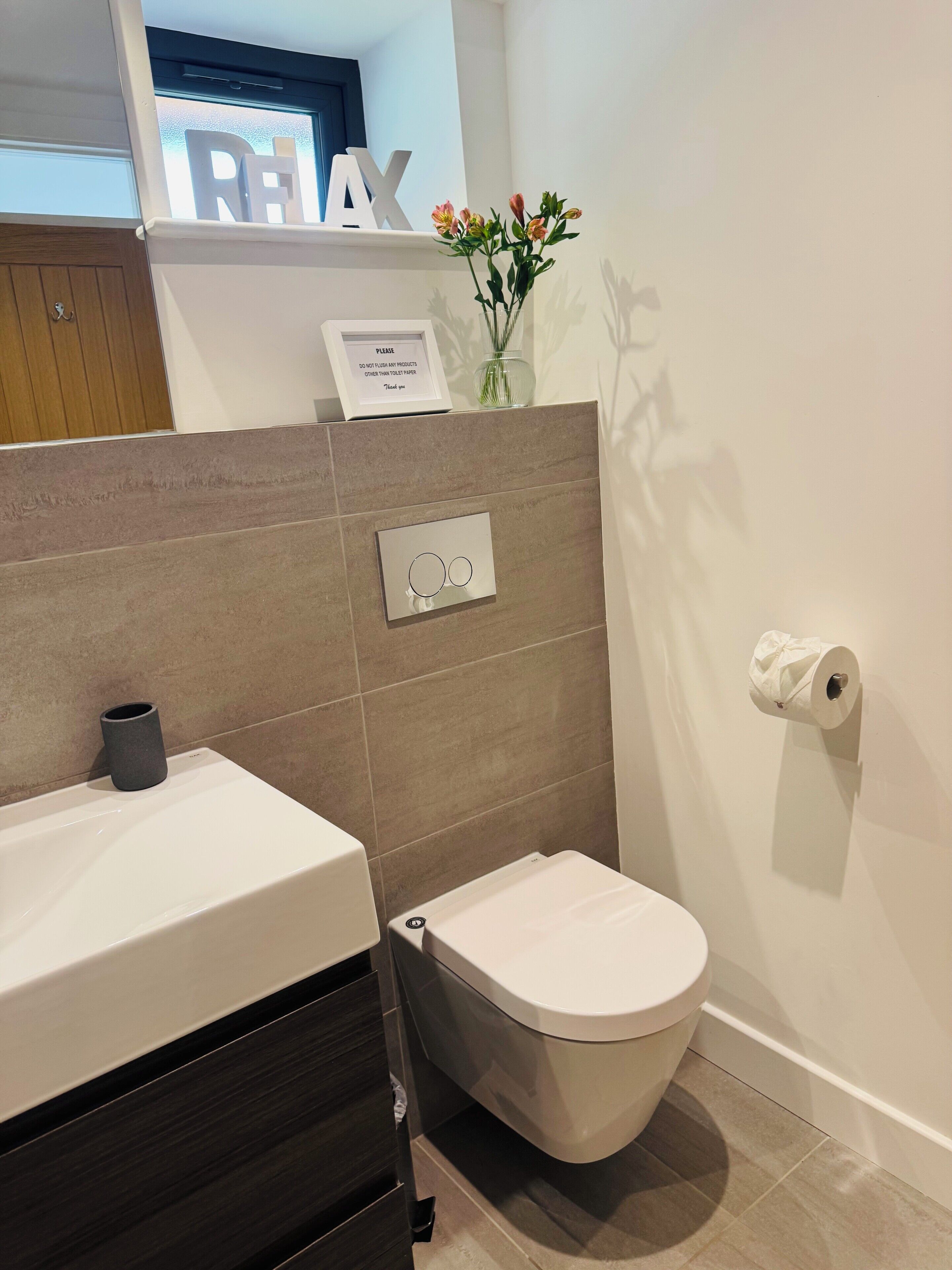 Une salle de bain équipée d’un WC, d’un lavabo, d’un distributeur de serviettes et d’un porte-rouleau de papier toilette.