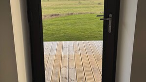 A door leading to a balcony with a view of a green field and distant hills. - SUPERIOR ACCOMMODATION WITH BREATHTAKING COUNTRYSIDE VIEWS (Glanton)