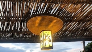 A thatched roof structure with a hanging light fixture and a view of a lake and mountains. - NDERE  ECHIFUUHA RESORT (Kisoro)
