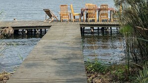 A wooden dock leading to a small island with several wooden chairs and a table set up for dining. - NDERE  ECHIFUUHA RESORT (Kisoro)