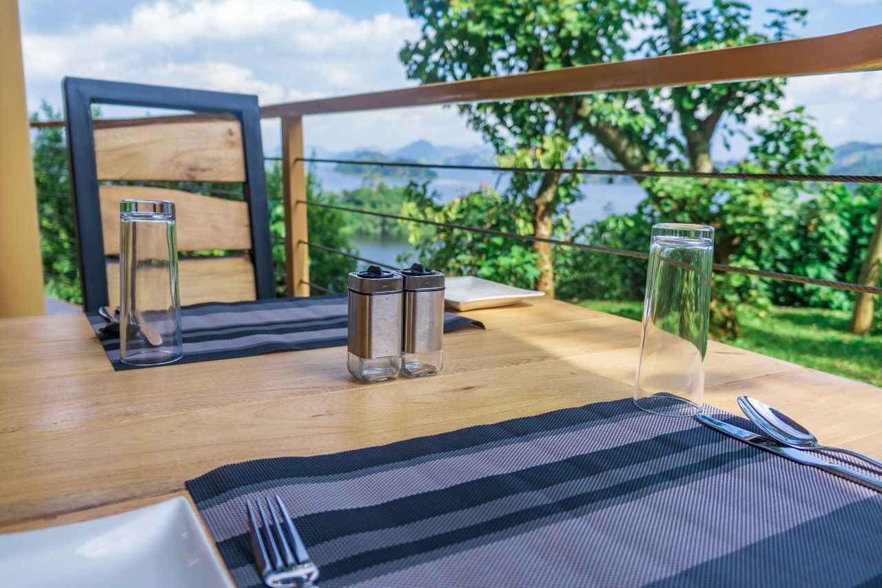Un tavolo da pranzo con vista su un lago e montagne, apparecchiato con bicchieri, conditori e posate.