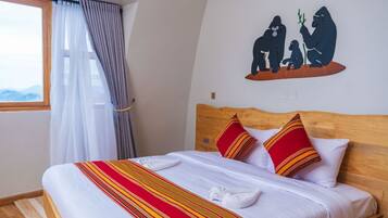 Een hotelkamer met een bed, een raam met gordijnen en een wanddecoratie van gorilla’s.