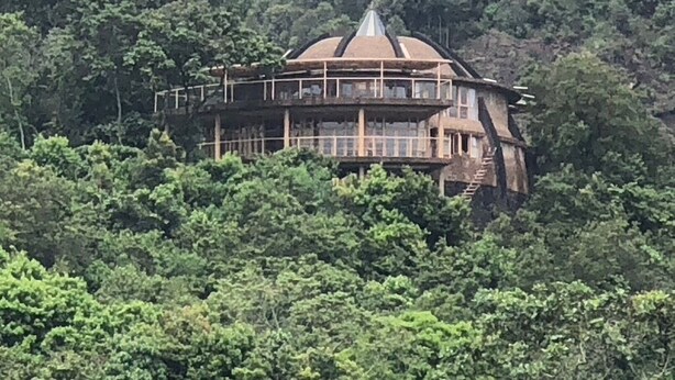A multi-level building with a dome-shaped roof, surrounded by dense forest. - NDERE  ECHIFUUHA RESORT (Kisoro)