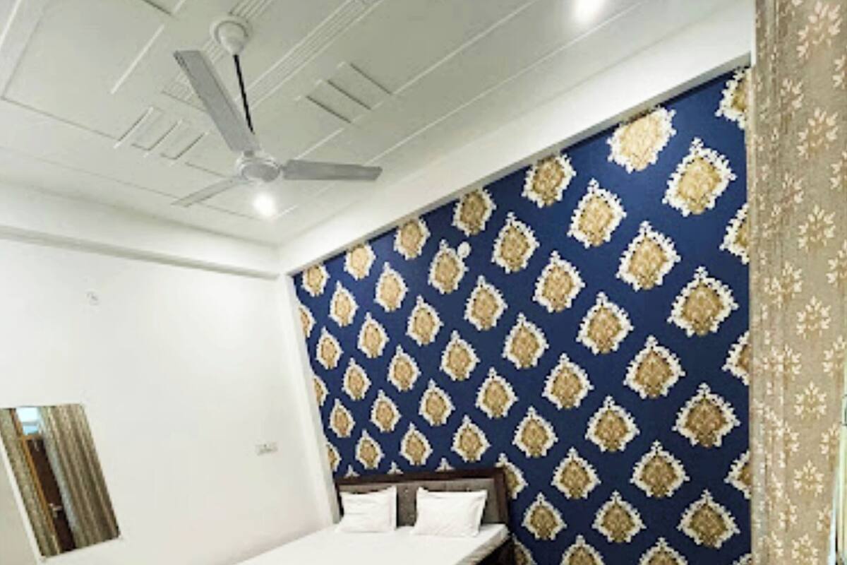 Un dormitorio con cama, ventilador de techo, papel tapiz estampado y suelo de mármol.