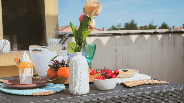 A table with a variety of food items, a vase with flowers, and a glass of drink.
