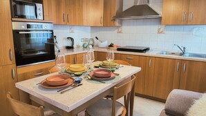 Una cocina con armarios de madera, estufa, microondas y pileta.
