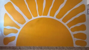 Een muur met een groot, gestileerd zonnedesign.