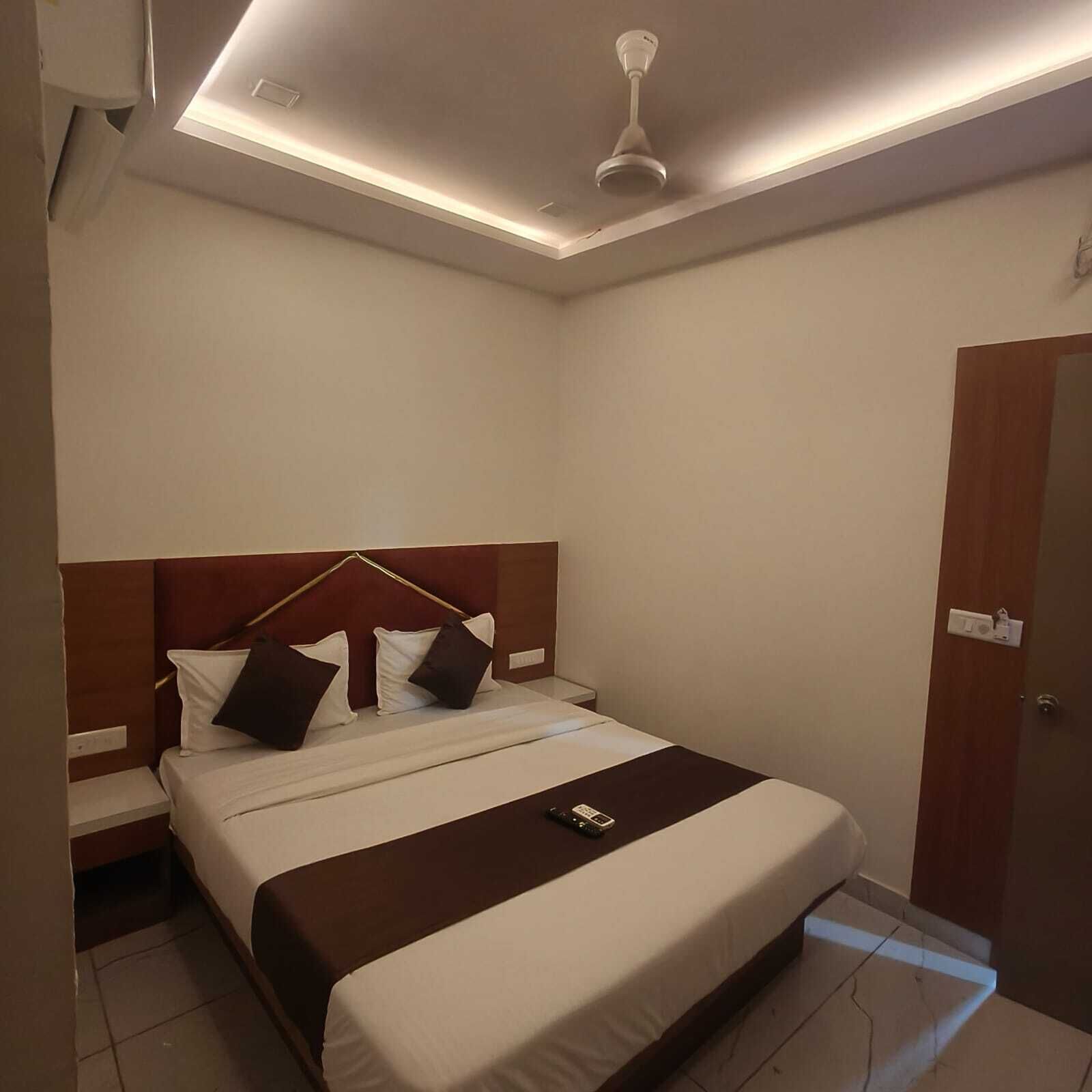 A hotel room with a bed, a nightstand, a ceiling fan, and a door.