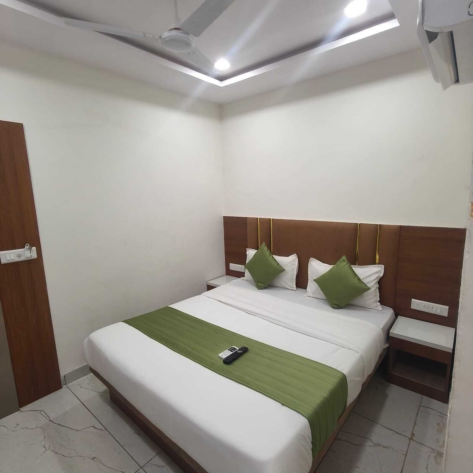 Una habitación de hotel con cama, mesita de noche y lámpara en el techo.