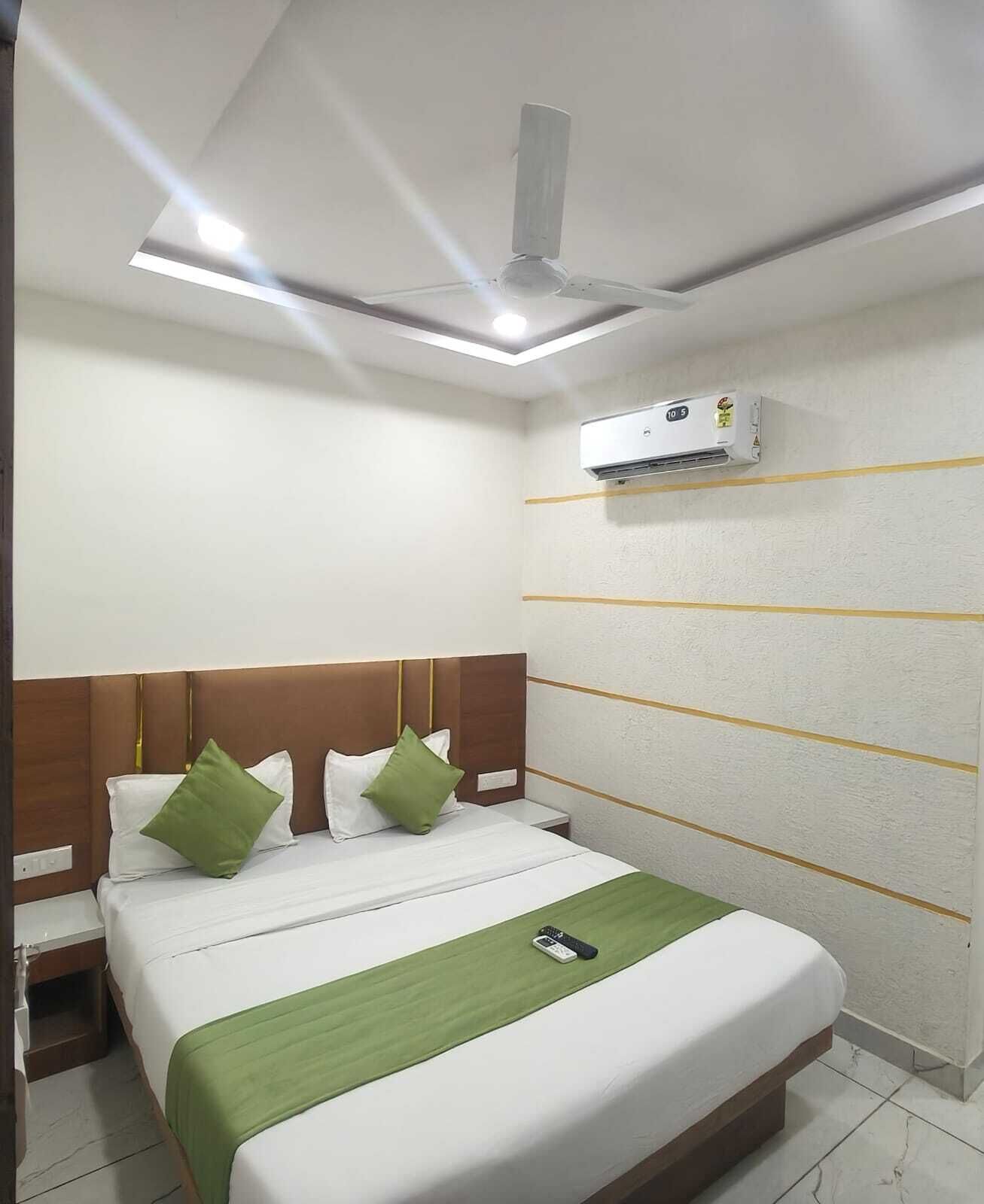Une chambre d’hôtel équipée d’un lit, d’une table de chevet, d’un climatiseur fixé au mur et d’un ventilateur de plafond.