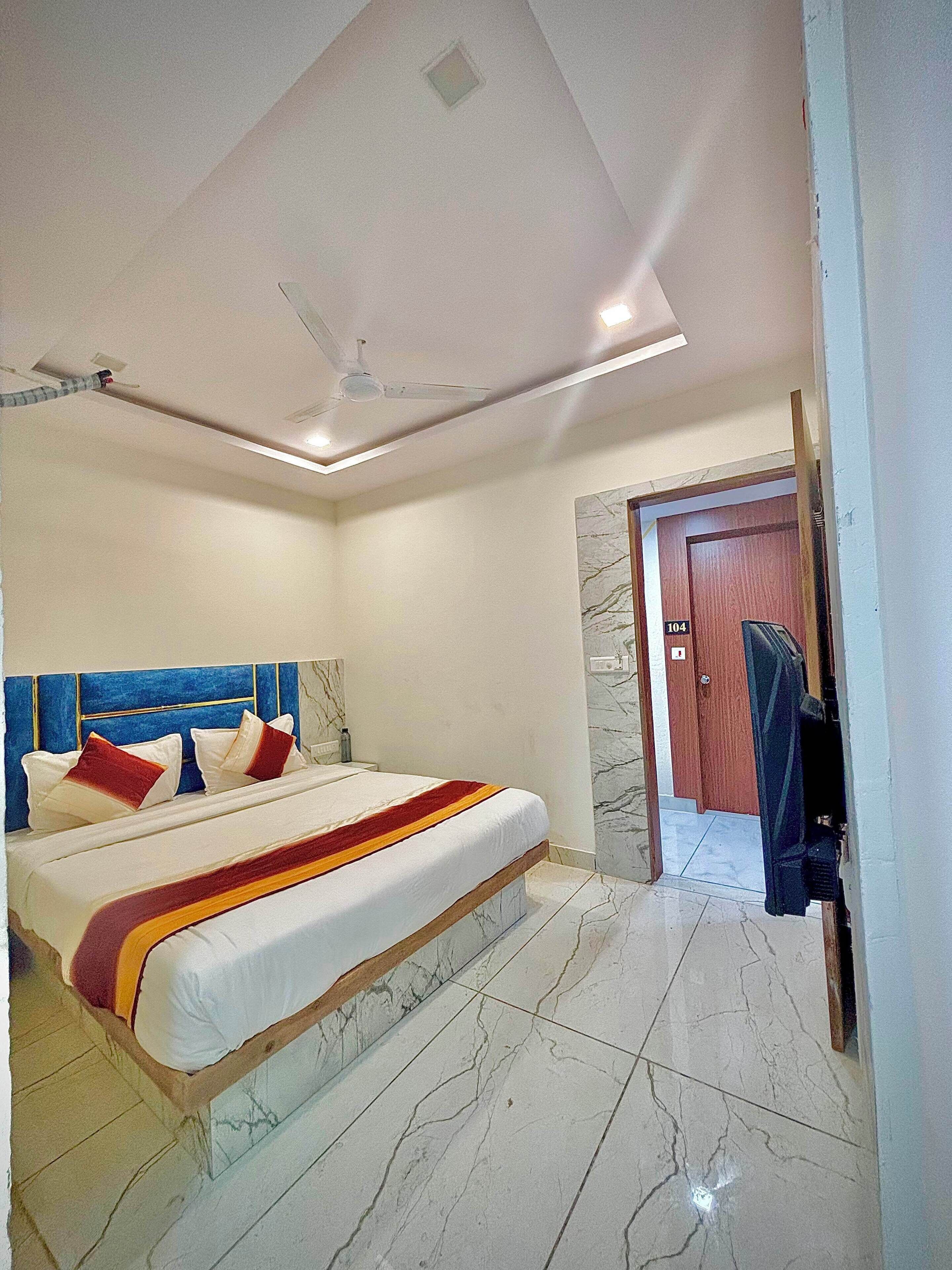 A hotel room with a bed, a ceiling fan, and a door leading to another room.