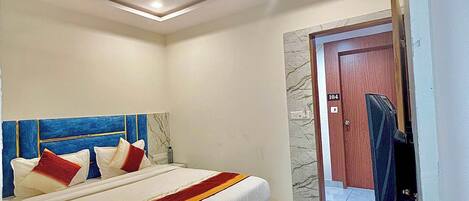 A hotel room with a bed, a ceiling fan, and a door leading to another room.
