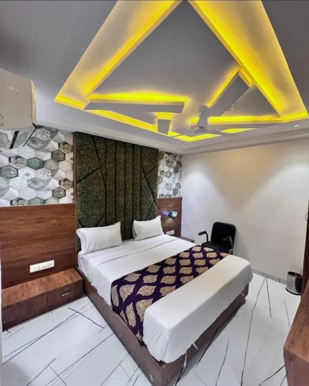 A modern bedroom with a bed, a nightstand, and a headboard with a geometric pattern.