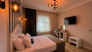 A bedroom with a bed, bedside table, desk, chair, TV, and a unique chandelier.
