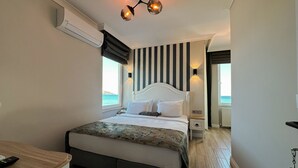 A hotel room with a bed, bedside tables, a desk, and a view of the sea. - Beyaz Ev Hotel Restaurant (Sinop)