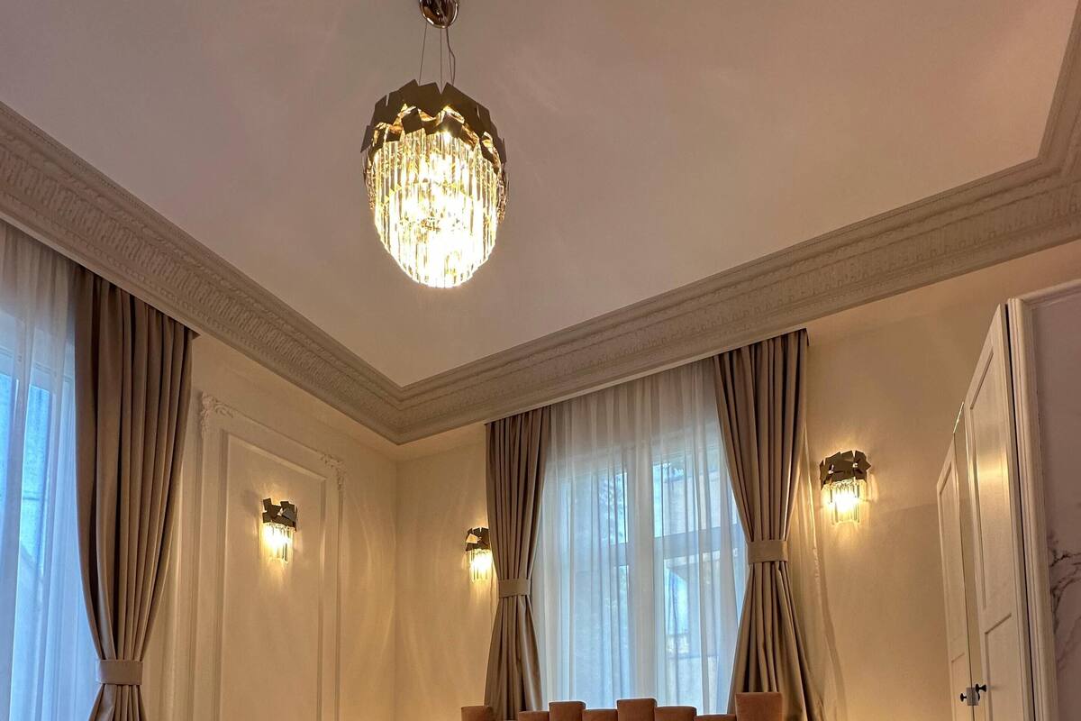 A spacious bedroom with a large bed, a chandelier, and two wall sconces.