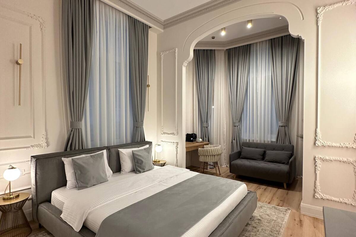 A modern bedroom with a large bed, a desk, and a sofa.