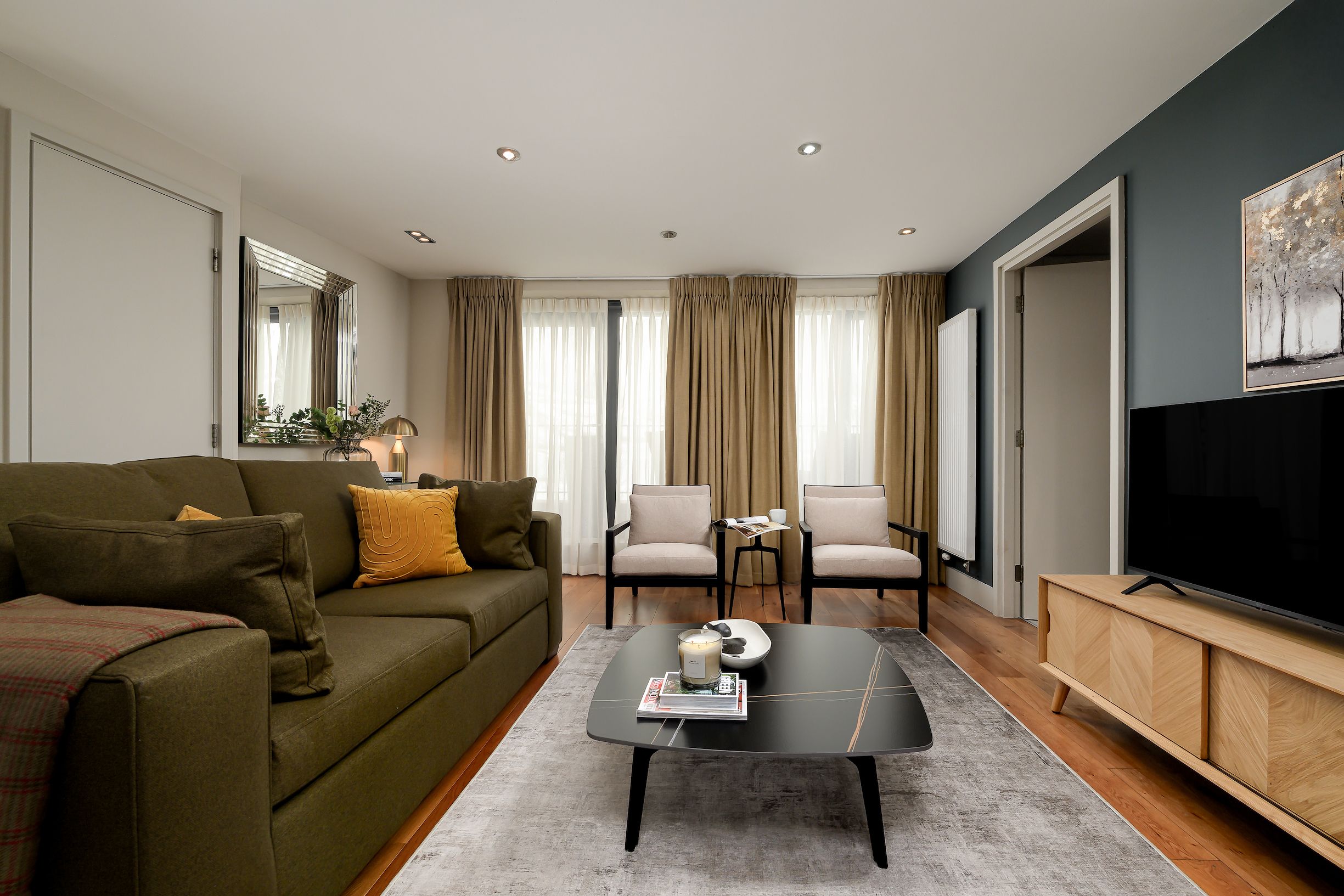 Un salon moderne avec un canapé, des fauteuils, une table basse et un téléviseur.