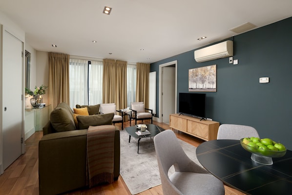 Una sala de estar moderna con un sofá, sillas, una mesa de centro y un televisor.