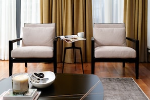 A room with two armchairs, a small table with a magazine, a candle, and a bowl.