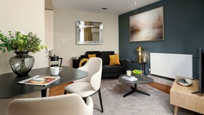 A modern living room with a sofa, coffee table, and a dining area with a table and chairs. - Monument | Executive Studio with Terrace (London)