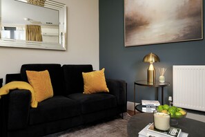 A modern living room with a black sofa, a round side table, a floor lamp, and a painting on the wall. - Monument Executive Studio with Terrace (London)