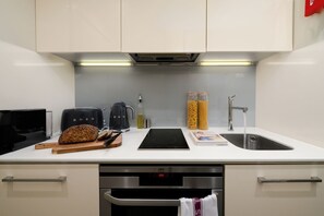 Une cuisine moderne équipée d’un four encastré, d’un évier et d’une machine à café.